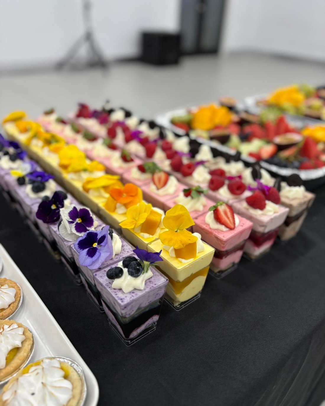 Rows of mousse dessert cups topped with edible flowers and berries